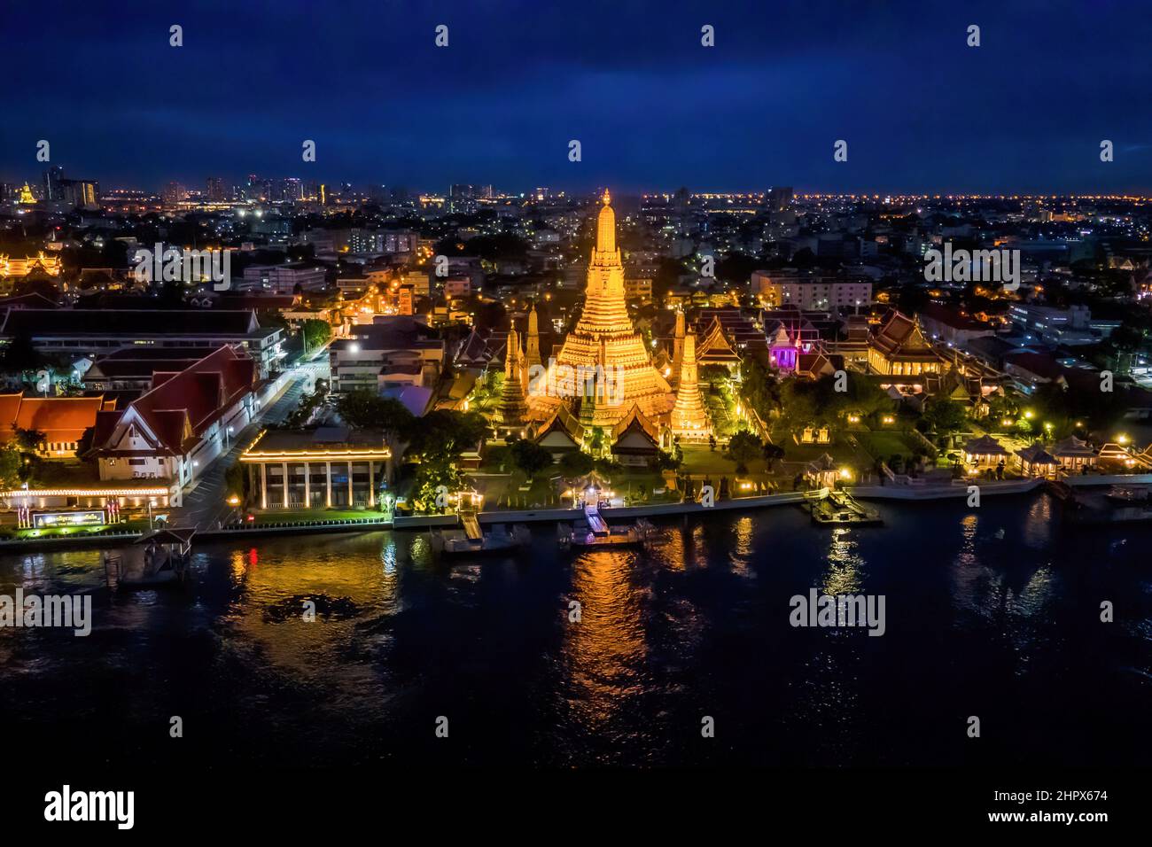 (EDITOR'S NOTE: Image taken with drone)Aerial view of Wat Arun, The Temple of Dawn, in Bangkok. Two of Thailand's most famous cultural heritage sites and tourist attractions, Wat Arun (Temple of Dawn) and The Grand Palace, are illuminated at night along the Chao Praya River in Bangkok. The Thai Government recently announced eased entry requirements for international tourists visiting Thailand amidst a surge in the Omicron variant of COVID-19 throughout the country, with cases topping 20,000 reported infections per day. Stock Photo