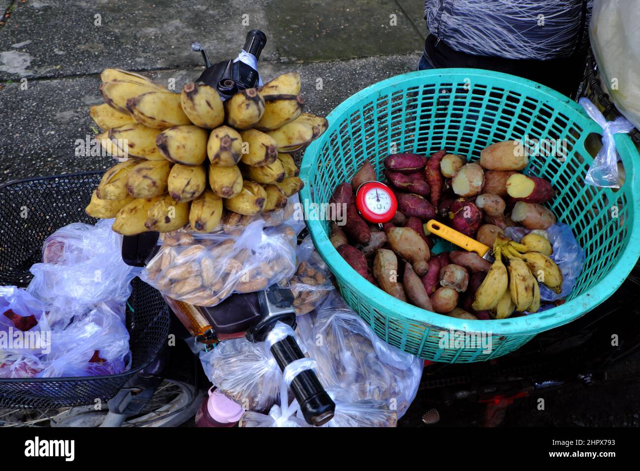 Mobile food store on motorbike to sell boiled banana, sweet potato, peanut, motorcycle transport basket at sidewalk, simple and cheap breakfast Stock Photo