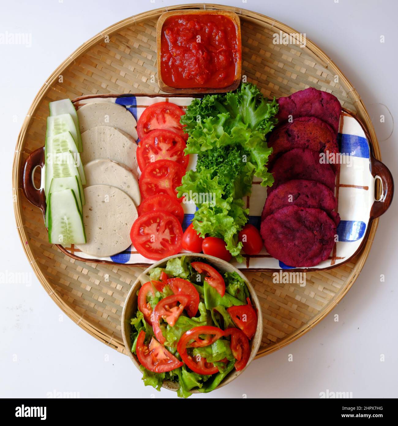 Amazing colorful raw material food for vegan hamburger from violet sweet potato with tomato sauce, salad, cucumber, healthy food for breakfast that ri Stock Photo
