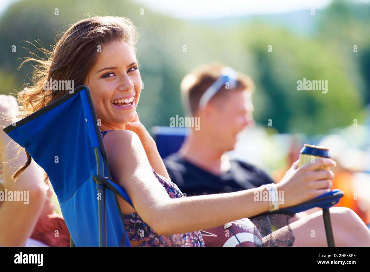 Enjoying her cold beer on a warm day. Portrait of an attractive young woman having a beer while sitting with her friends at a campsite. Stock Photo
