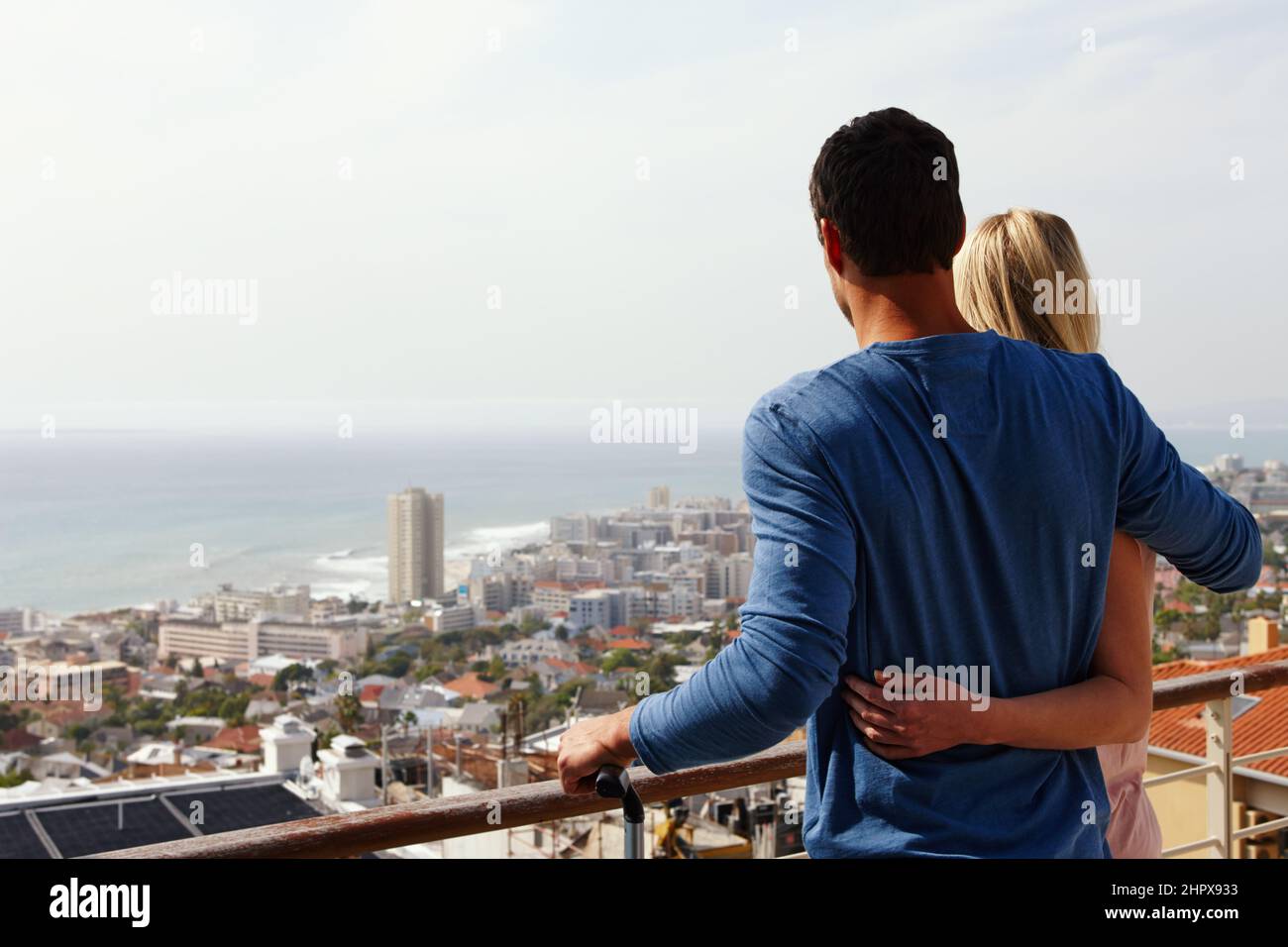 We love our new place. A happy couple standing on a balcony looking over the view. Stock Photo