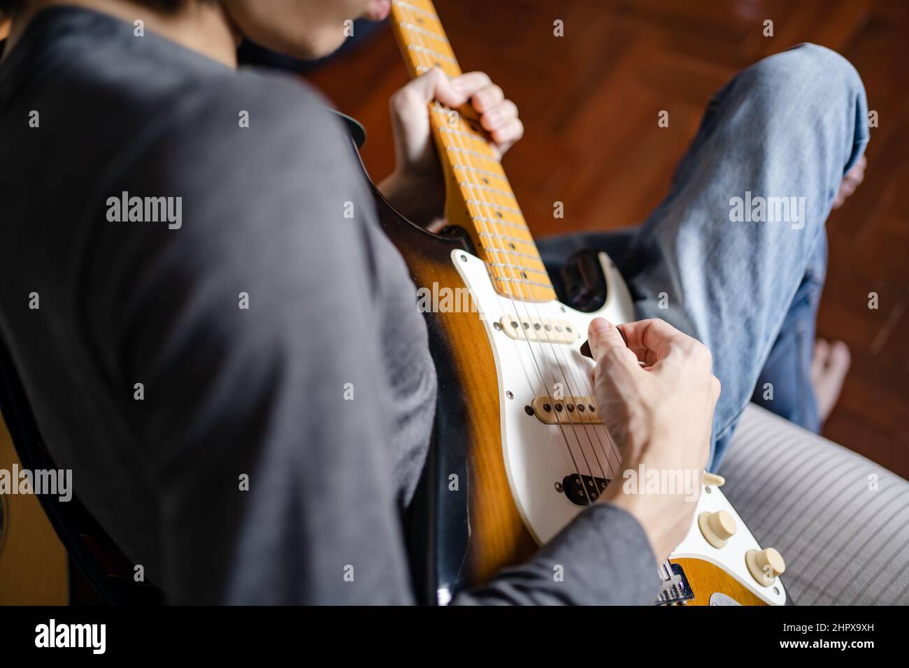 A man playing electric guitar on a bed Stock Photo