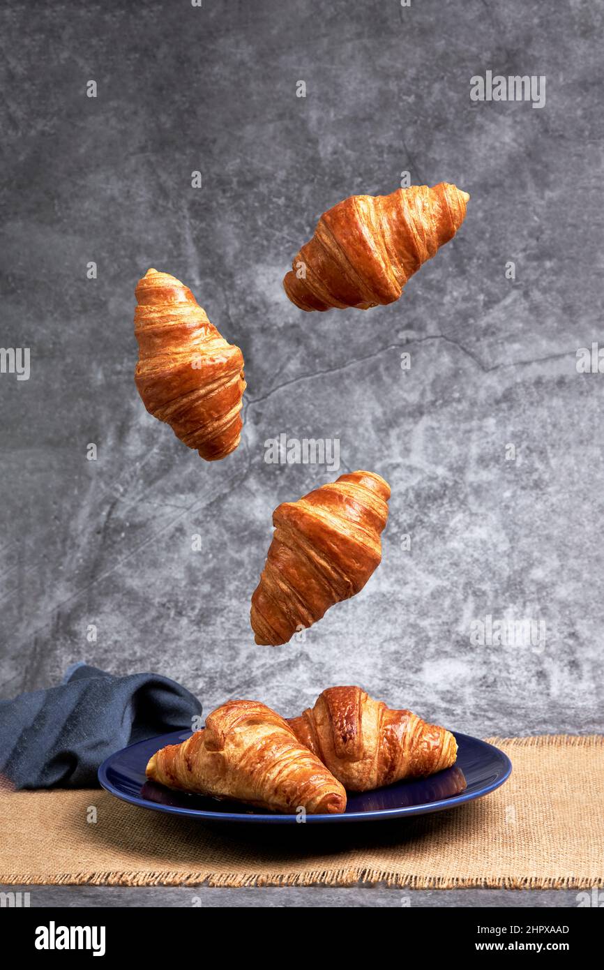 Group of croissants falling on a blue plate. Healthy breakfast. Sweets