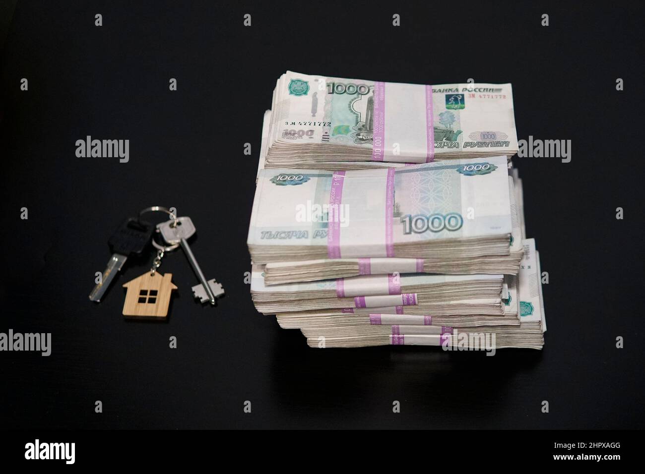Banknotes of Russian rubles and keys to the apartment on the black table. Estate sale. The deal for the sale of the apartment. Concept. Stock Photo