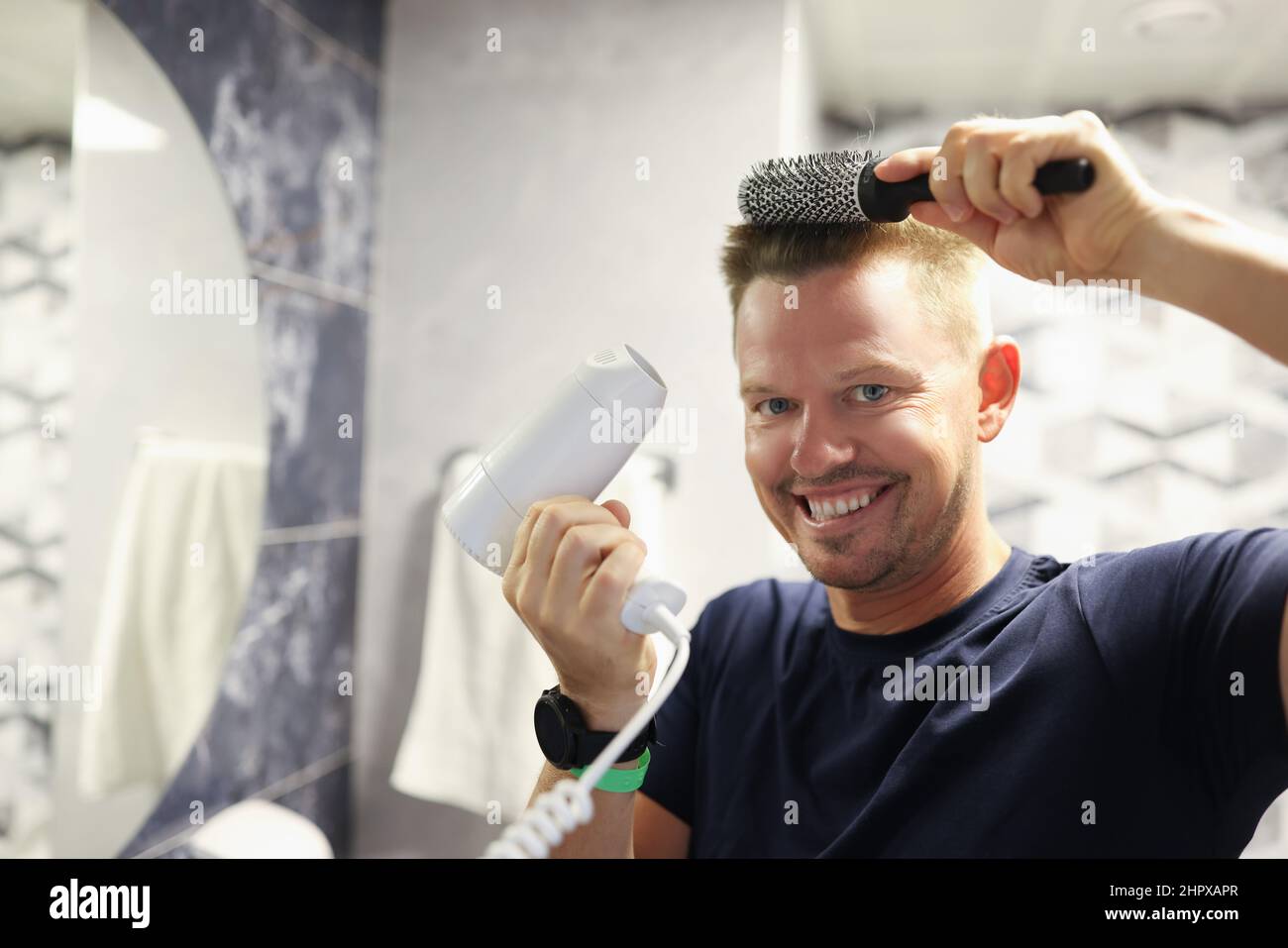 Happy man doing his own blow-drying at home Stock Photo