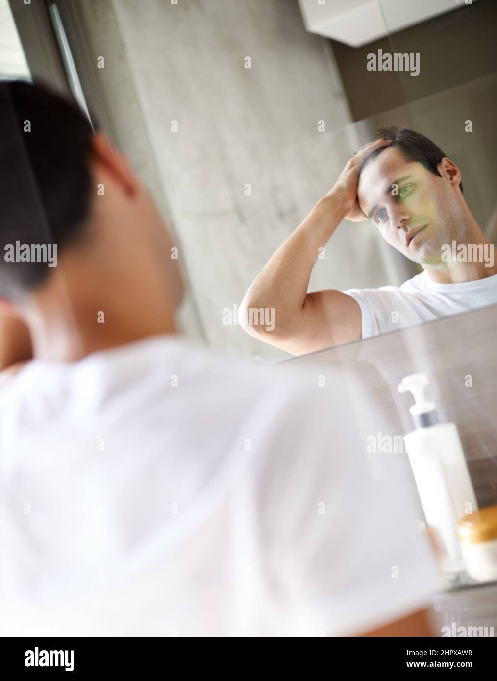 What should I start with this morning. Cropped shot of a young man looking at himself in the mirror. Stock Photo