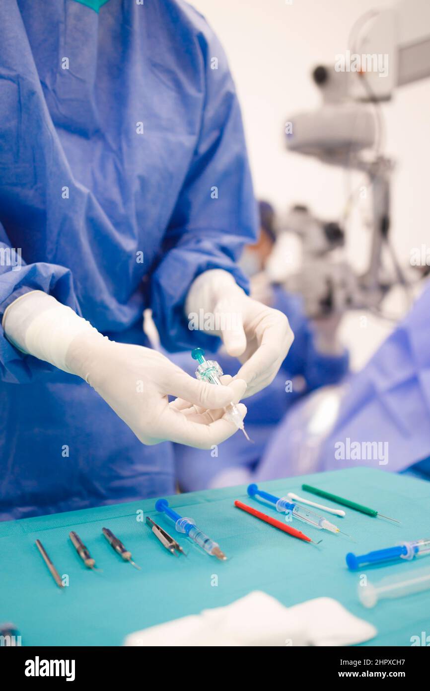 A nurse taking the syringe during a cataract surgery in an eye clinic Stock Photo