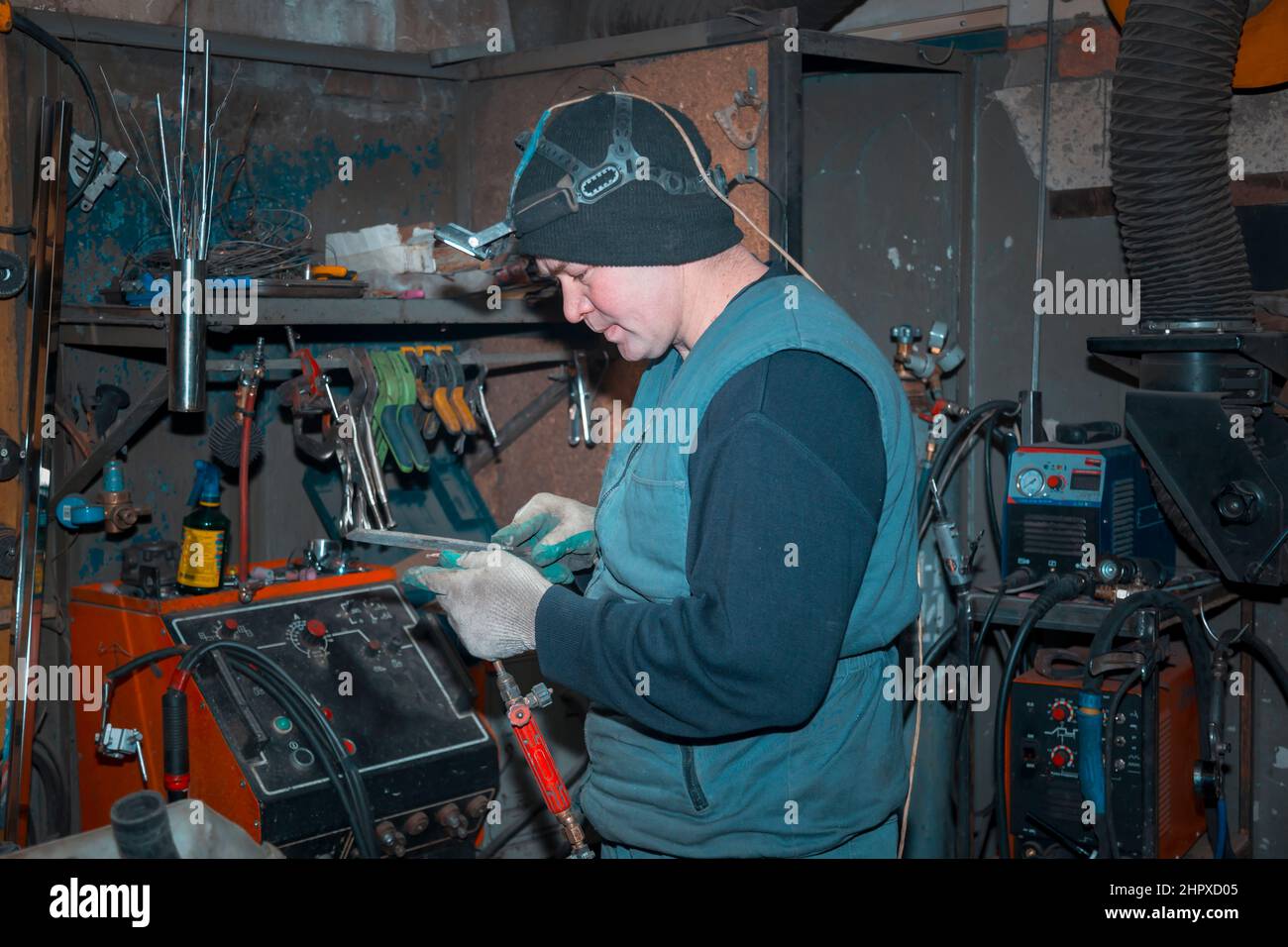 Gas welder cleaning a gas burner with a file at the workplace Stock Photo