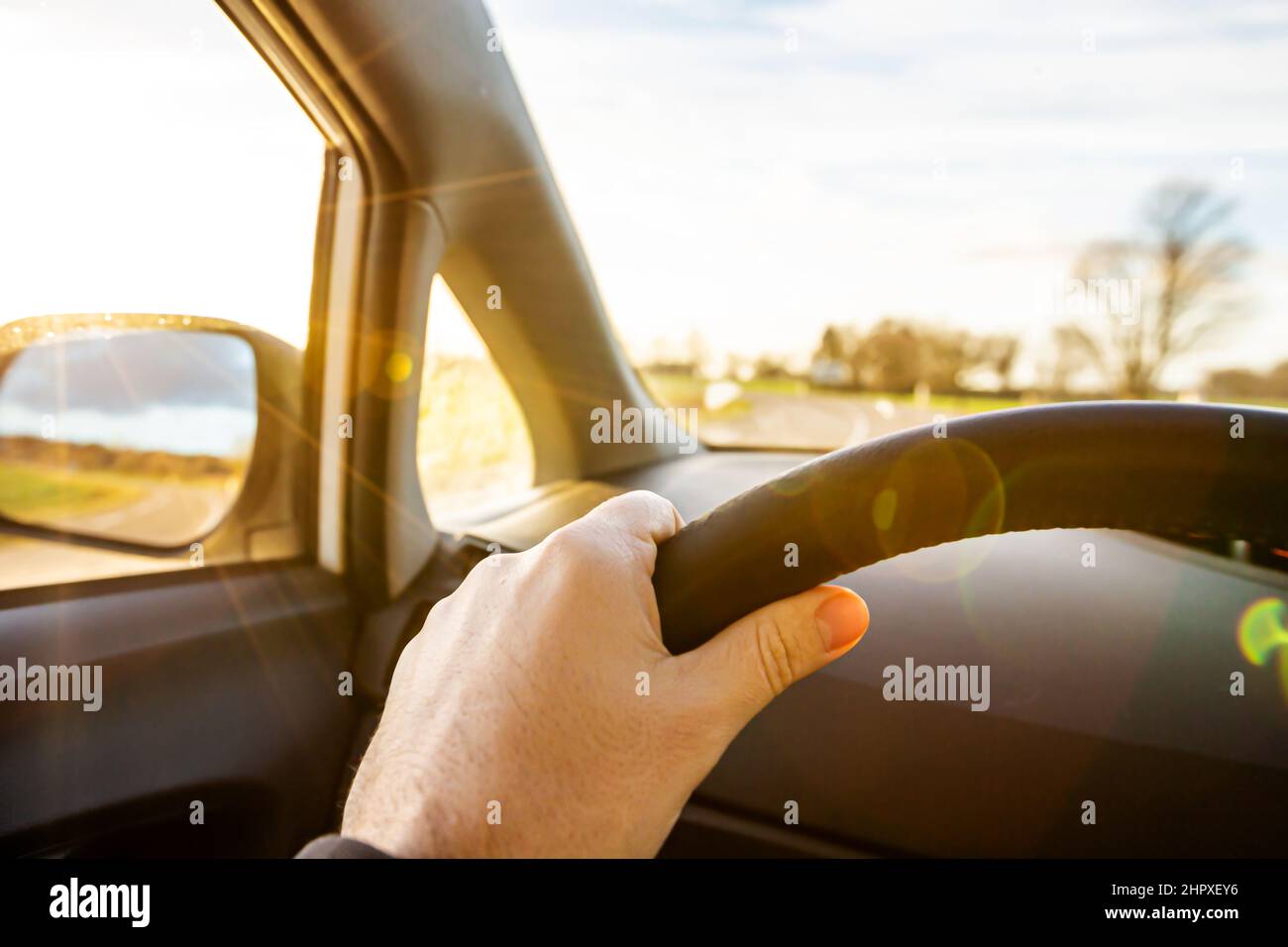 Hand holding steering wheel over morning sunrise Traveling with car concept . Car insurance concept Stock Photo