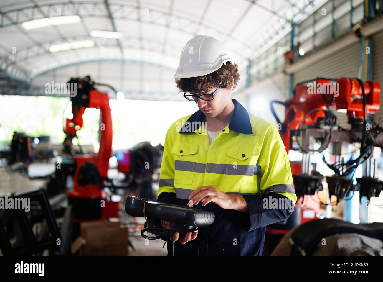 engineer checking control panel and teaching new Automatics robot arm and operating control machine in factory. Stock Photo