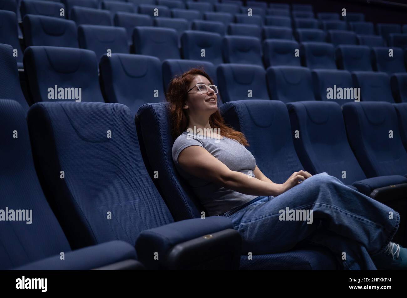 Caucasian red haired woman sits on the front row in a cinema in an