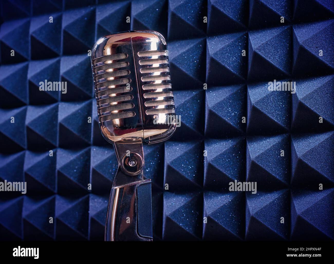 Old style mic, in an isolated recording studio booth. Retro, professional equipment on a music template, with copy space for text Stock Photo