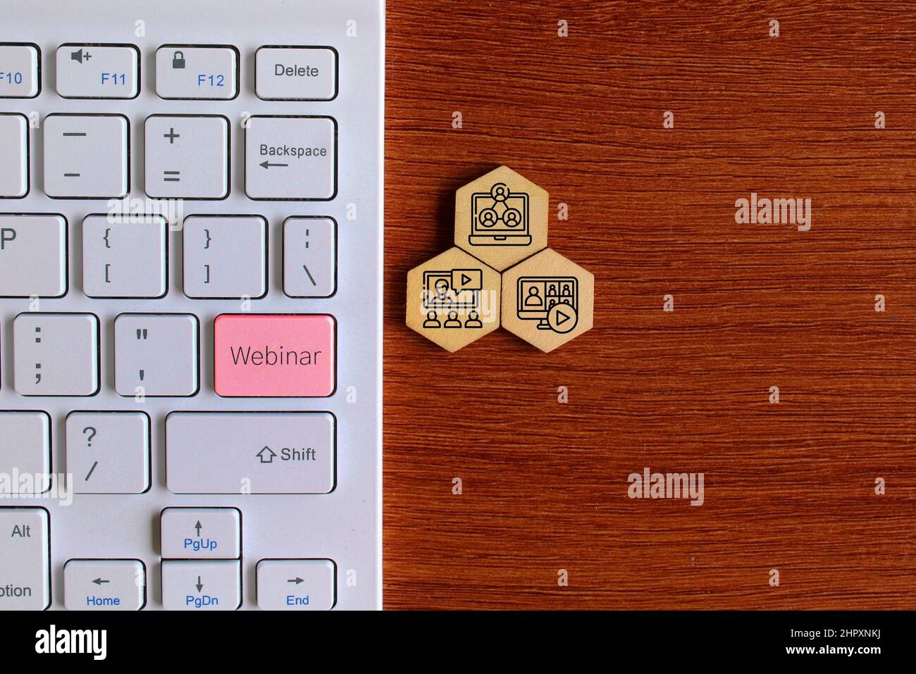 Top view image of keyboard with text WEBINAR and wooden hexagon shape with webinar icon. Stock Photo