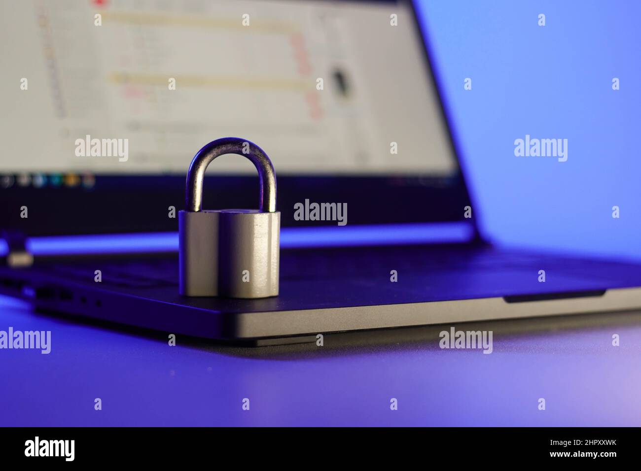 Locked metal padlock on a laptop keyboard over blue background. Cyber