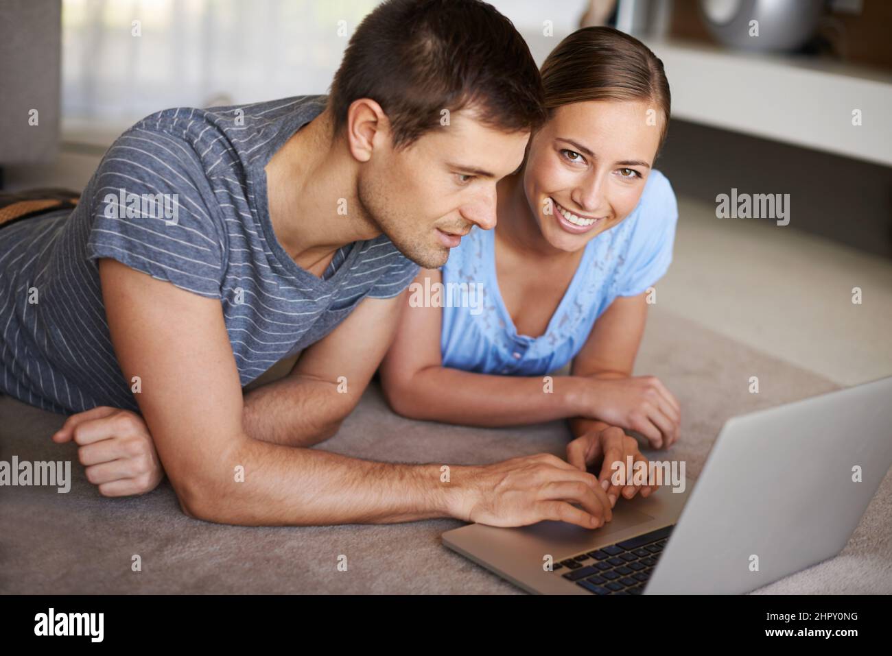 Getting all their info online. Shot of a happy young couple using a laptop on the floor together. Stock Photo