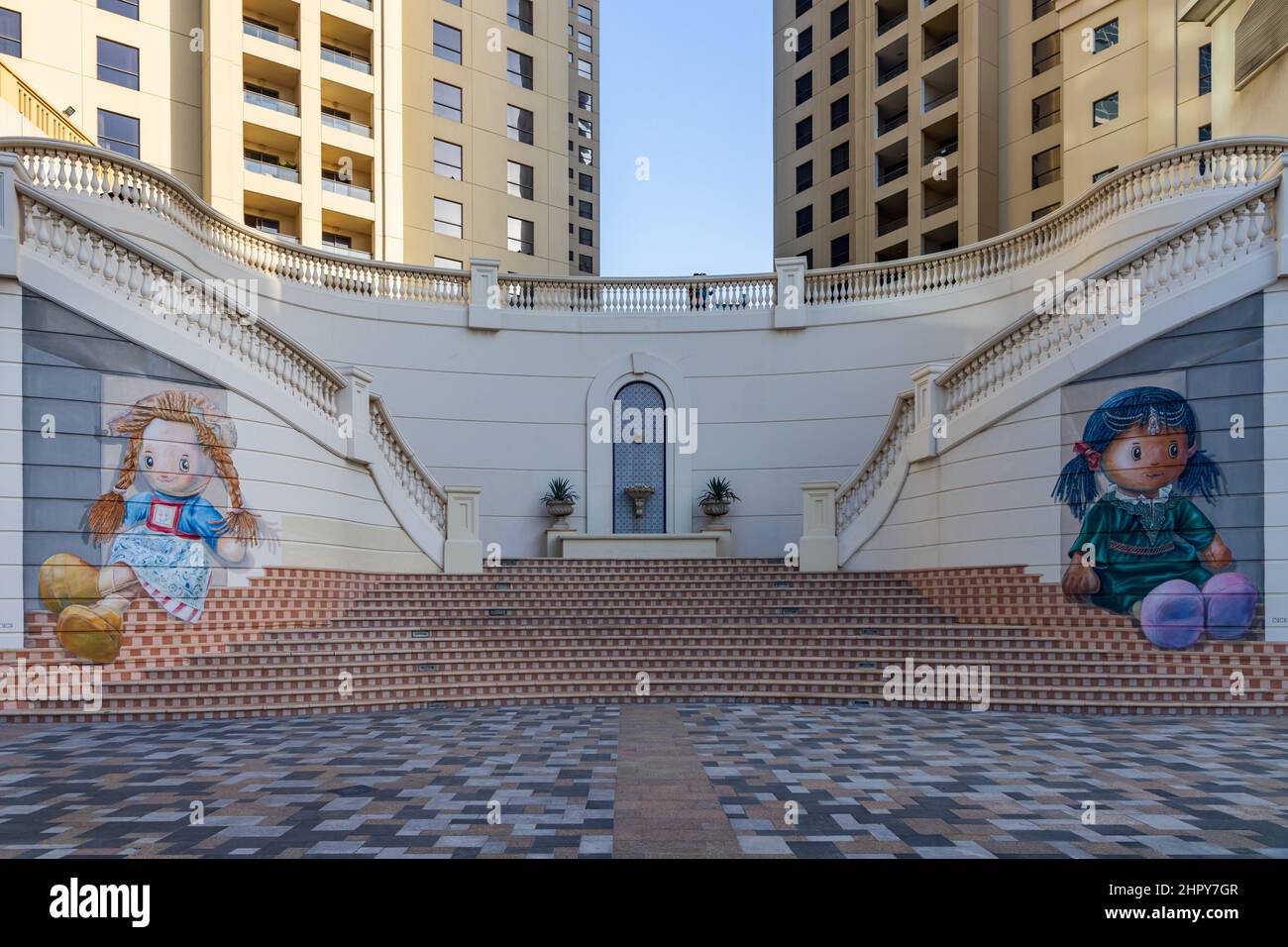 3D mural of 2 dolls sitting on steps in Dubai Marina area, United Arab Emirates. Stock Photo
