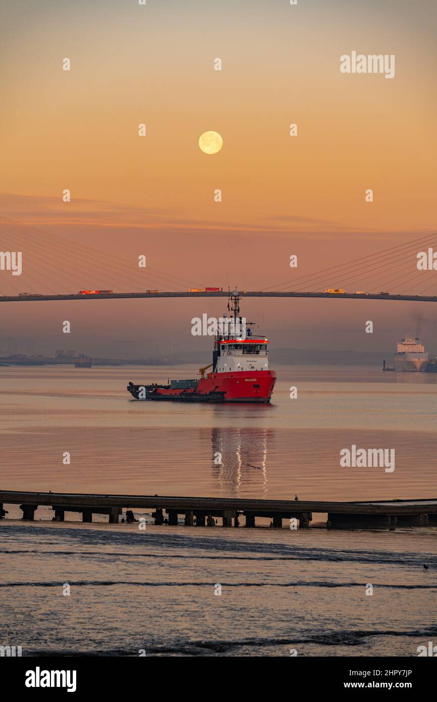Dawn and Moonset over the Dartford bridge on a cold winters morning with Tug in Foreground Stock Photo