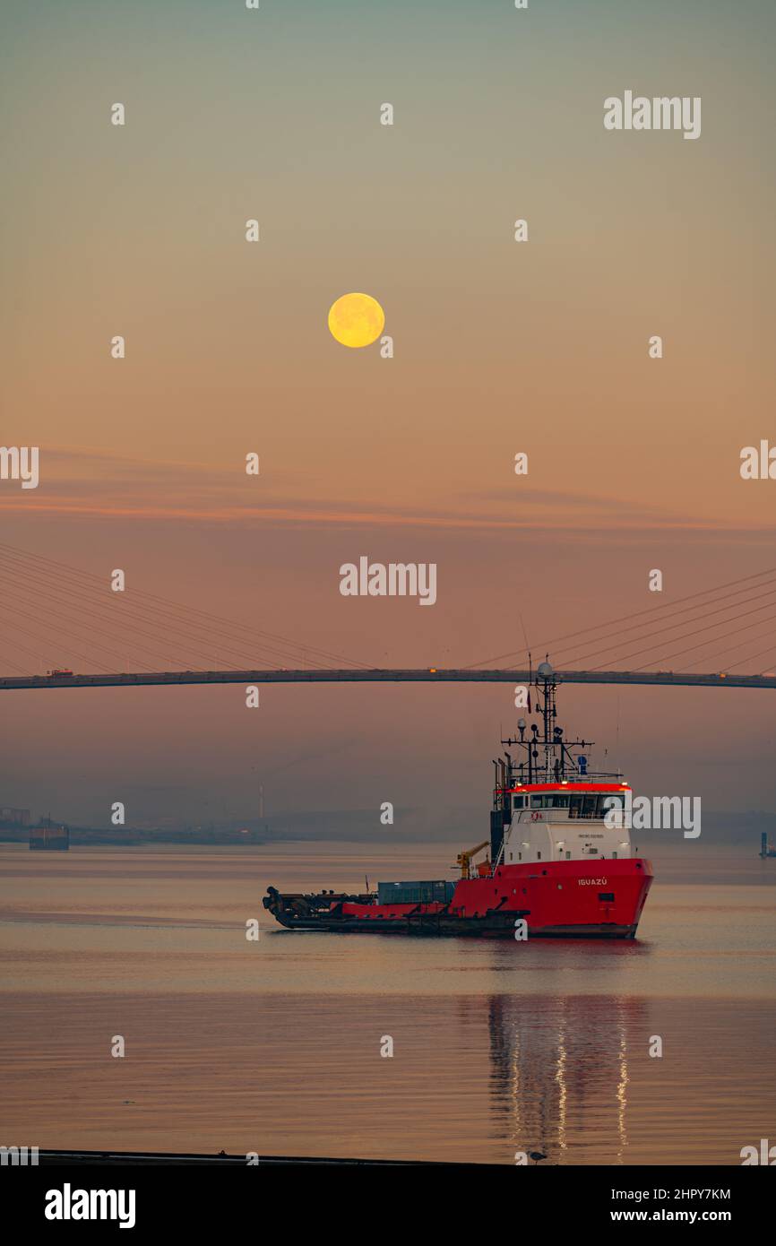 Dawn and Moonset over the Dartford bridge on a cold winters morning with Tug in Foreground Stock Photo