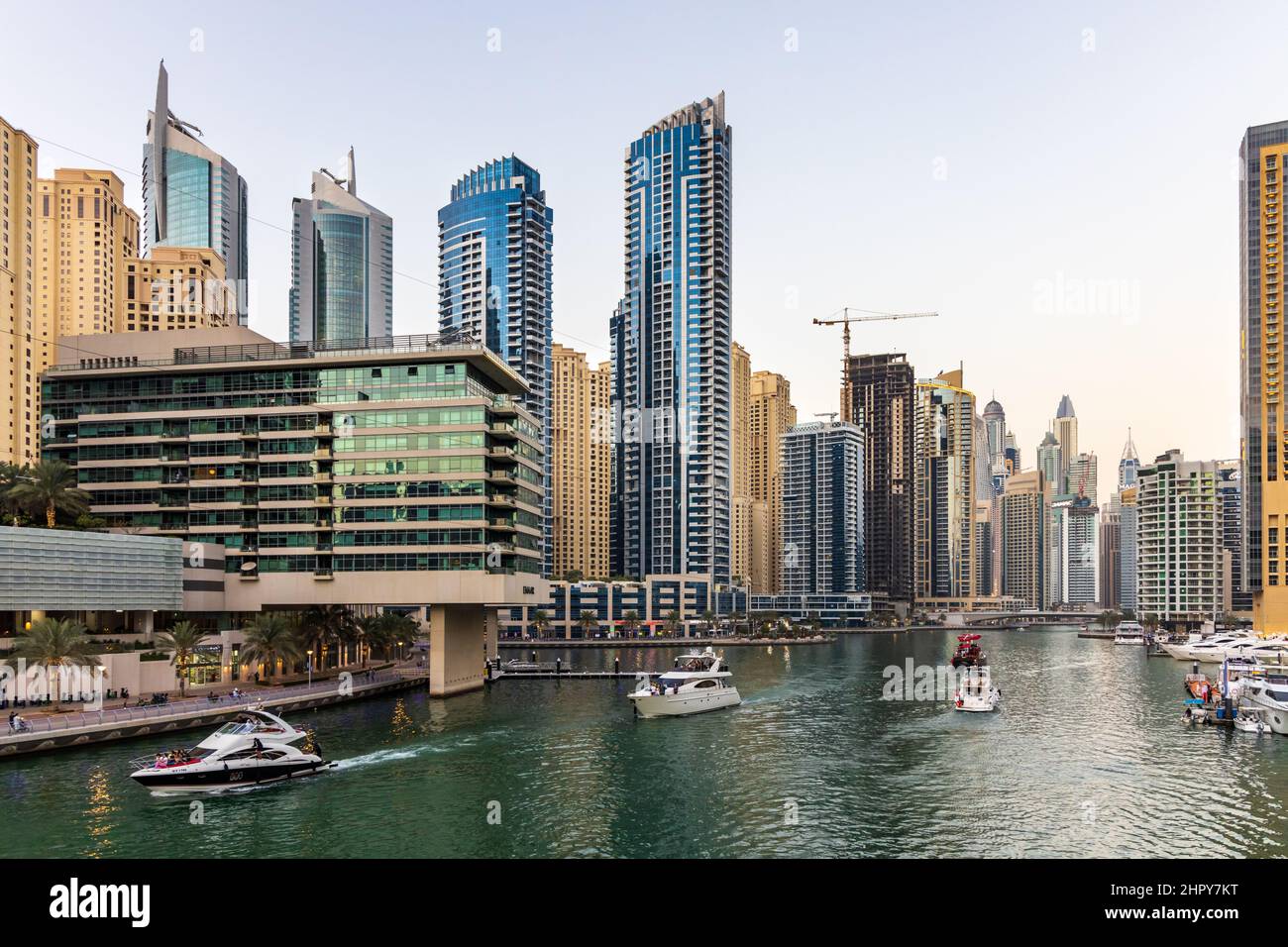 Yachts and boats cruising in Dubai Marina, surrounded by numerous residential skyscrapers, restaurants, shops and hotels. UAE Stock Photo