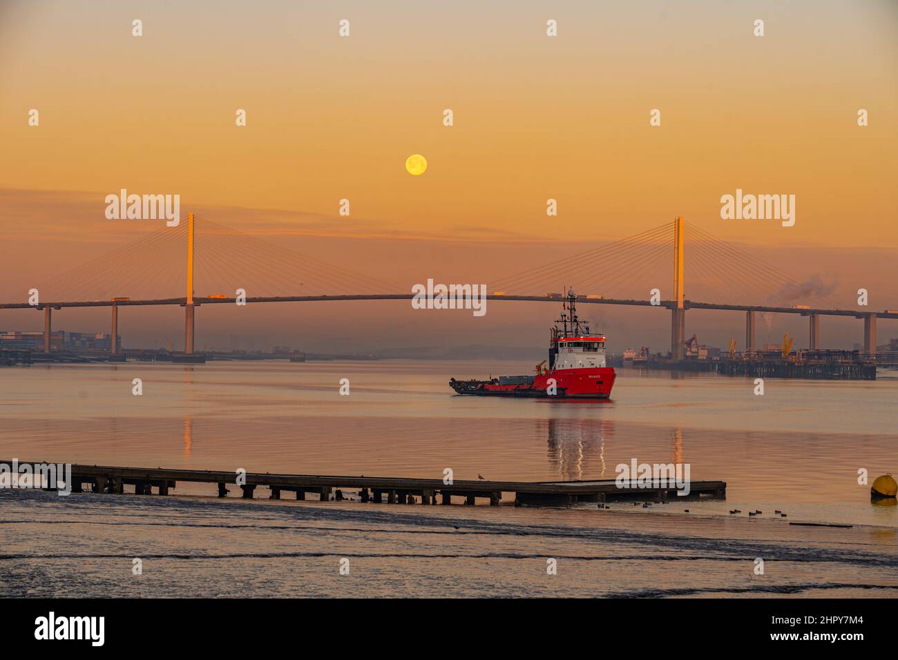 Dawn and Moonset over the Dartford bridge on a cold winters morning with Tug in Foreground Stock Photo