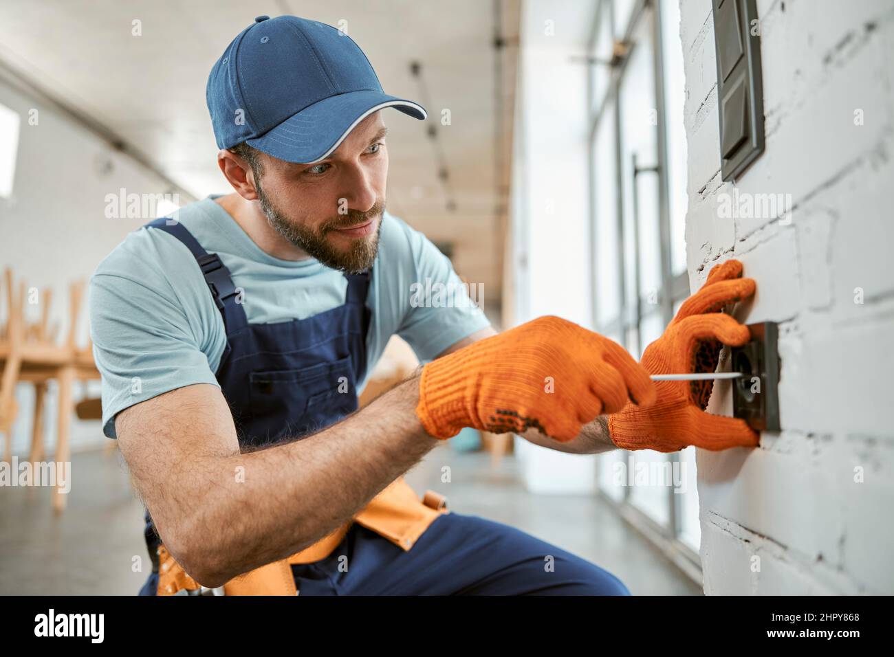 Bearded man fixing electrical wall socket with screwdriver Stock Photo