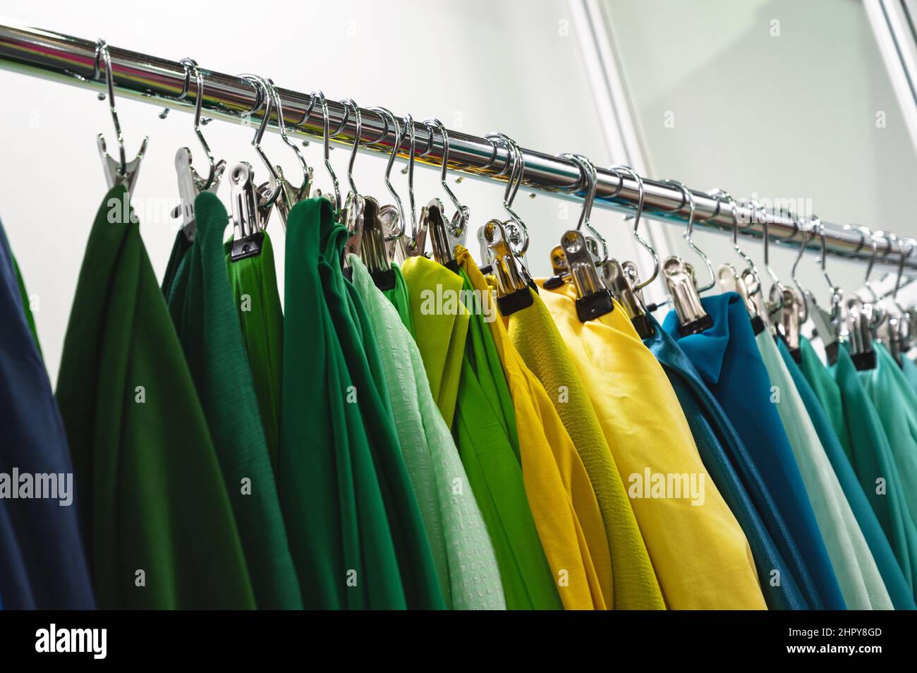 Samples of green yellow and blue fabrics hang on rack bar Stock Photo ...