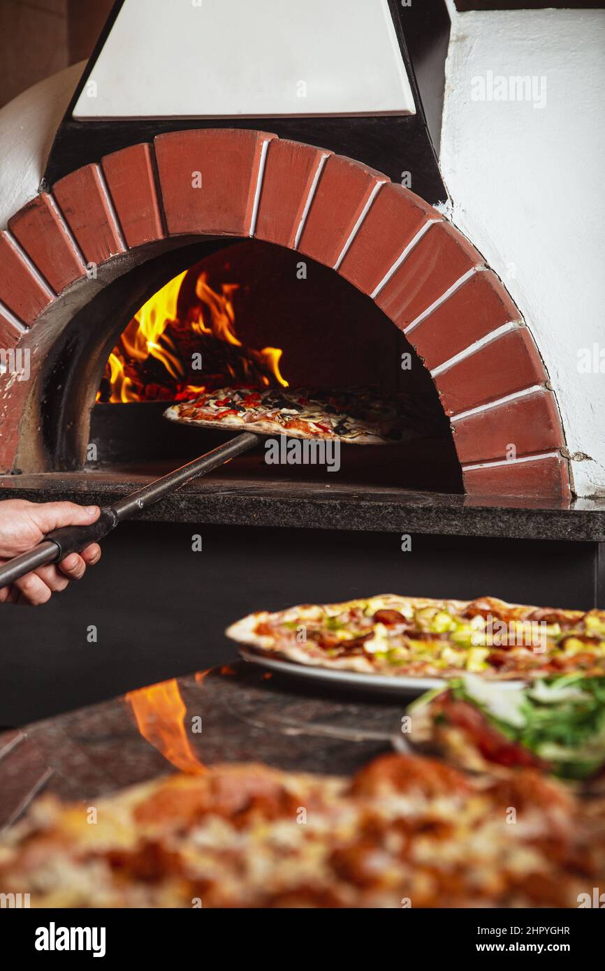 Vertical shot of traditional Italian pizza cooking in a wood stone oven Stock Photo