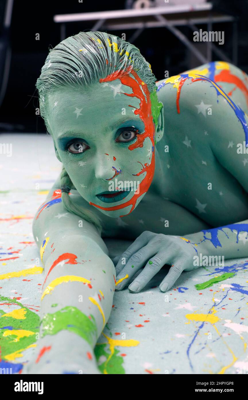 Bodyart artist Jörg Düsterwald has created a series of works of art on the subject of 'diversity' with various photo model types. In the production halls of the cooperating company Vorwerk flooring in Hamelin, he gave the pregnant model Anastasia body painting to match the sponsored floor covering and then applied traces of liquid paint. Stock Photo