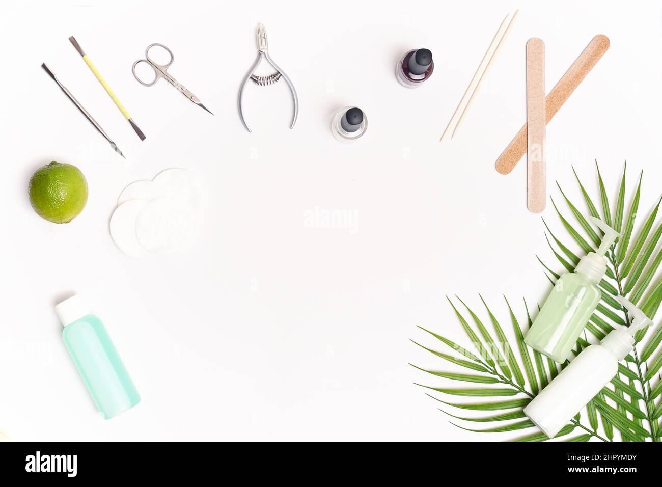 Nail care. Flat lay manicure or pedicure tools on white table with green leaves. Stock Photo