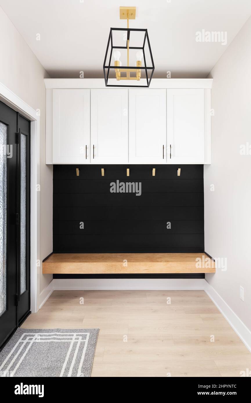 A modern farmhouse entryway with bench seating, black shiplap, white