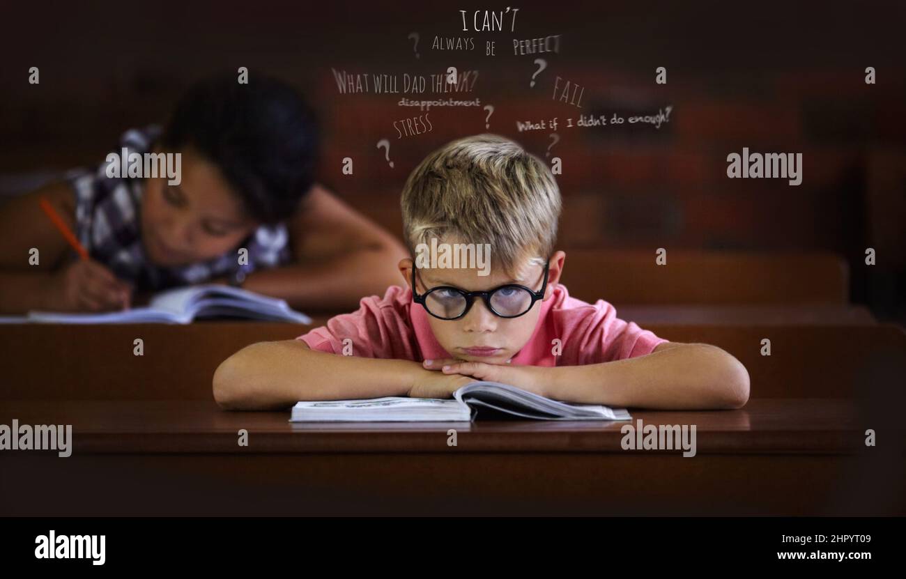 Confused and struggling to learn - Learning disabilities. Young boy feeling overcome with boredom in the classroom. Stock Photo
