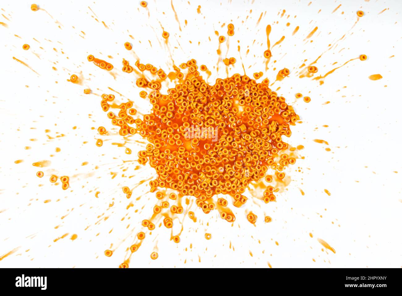 Spaghetti rings in tomato sauce splattered on a white background Stock Photo