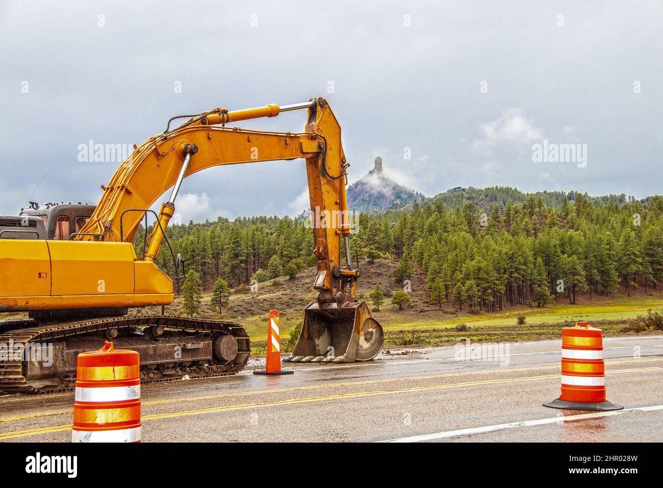 Chimney Rock National Monument, in Colorado USA with large backhoe working on highway and safety cones on drizzly foggy day Stock Photo