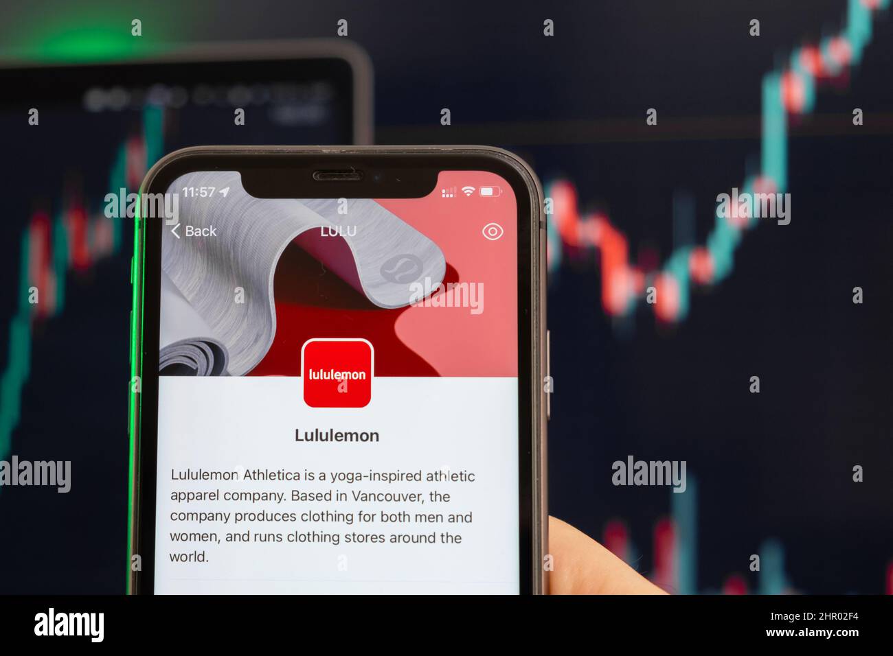 Lululemon stock price increasing on the trading market with uptrend line graph bar chart on the background. Man holding a mobile phone with company logo, February 2022, San Francisco, USA Stock Photo