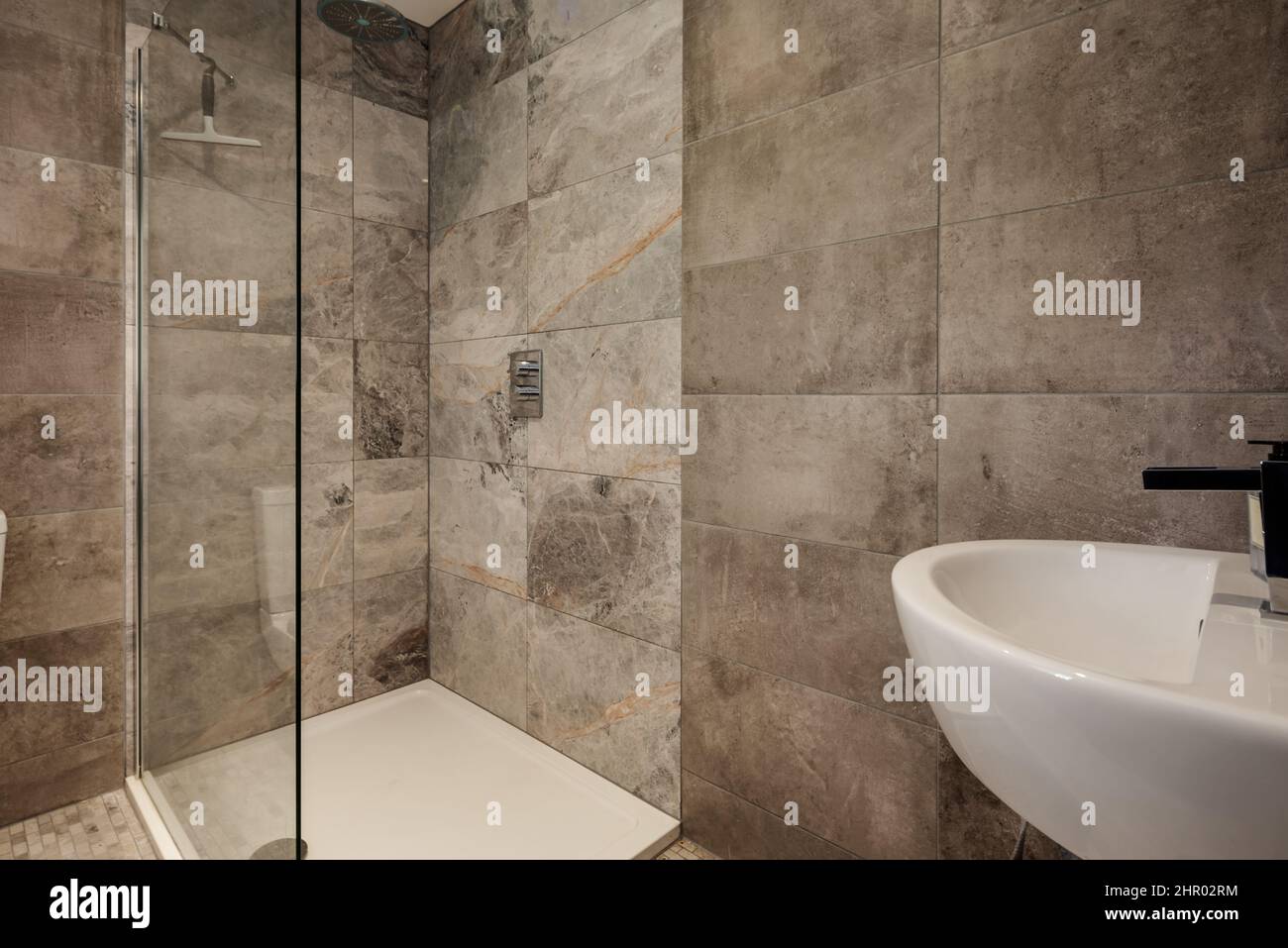 Fully tiled shower and powder room with glass shower cubicle Stock Photo