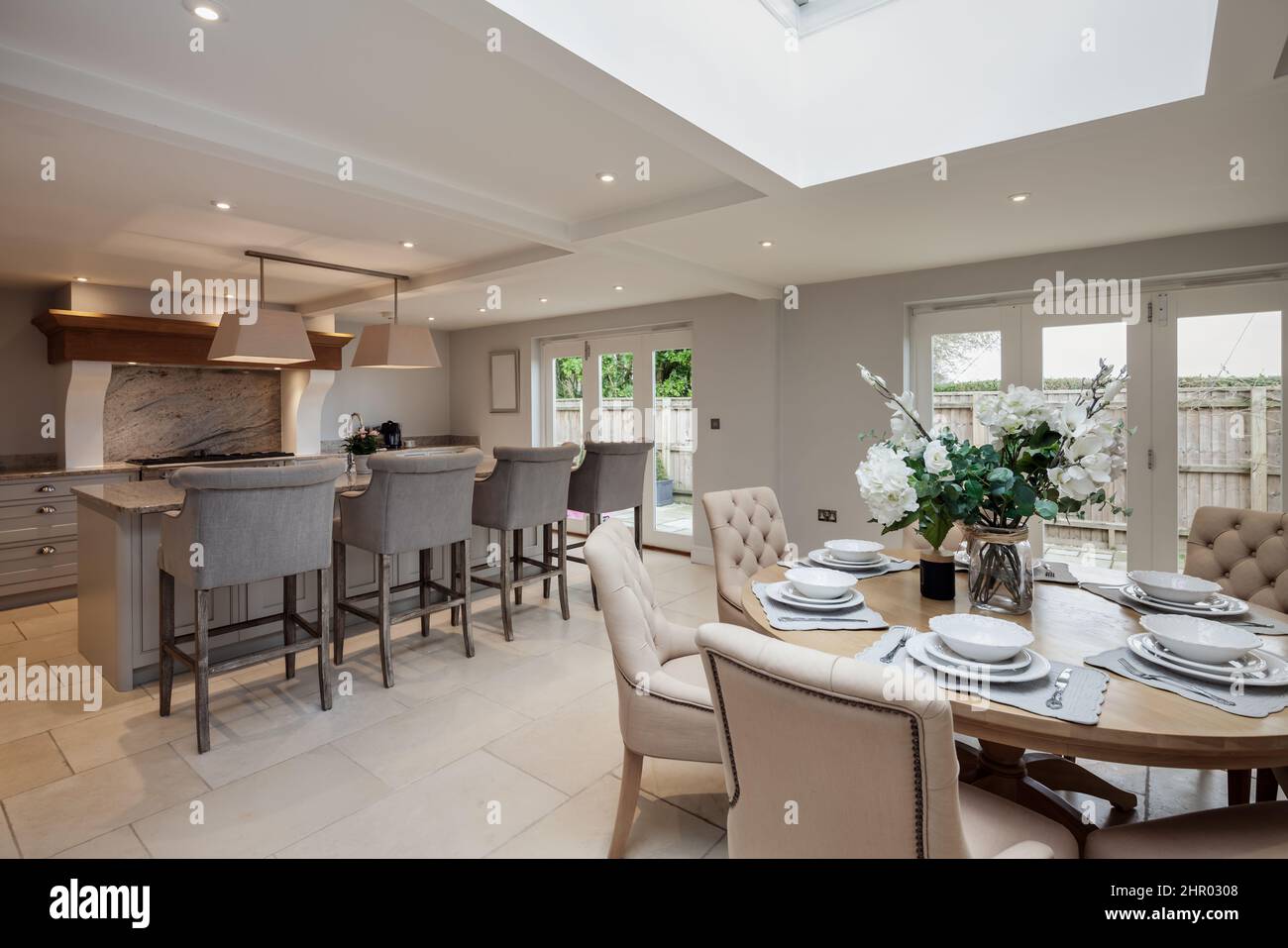 Exceptional luxurious chic fitted kitchen breakfast room with built in appliances including range cooker and marble granite counter tops,  upholstered Stock Photo