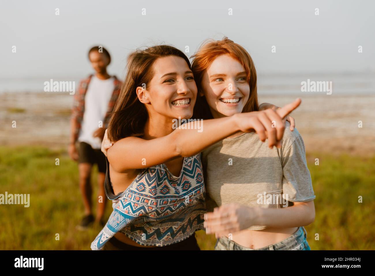 Young white women hugging and pointing finger aside while walking outdoors Stock Photo