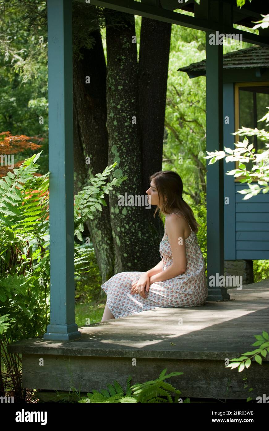 Young woman sitting on porch Stock Photo - Alamy