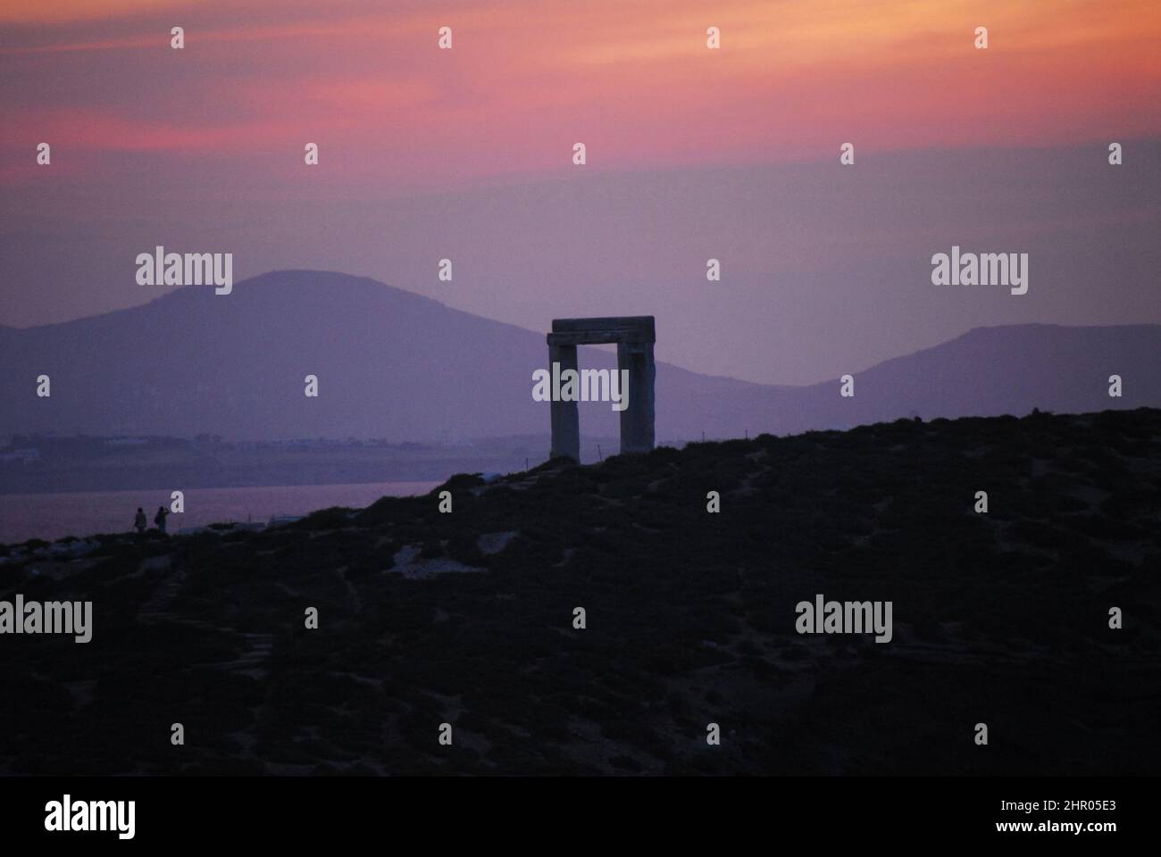Panorama of dramatically colorful sunset over the ruins of the ancient Temple of Apollo, Naxos, Greece. Note the distant people are not recognizable. Stock Photo