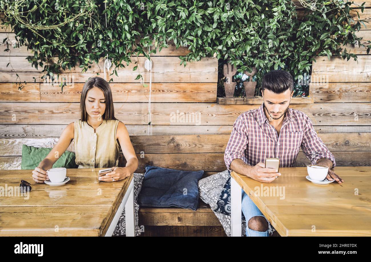 Fashion couple in disinterest moment ignoring each other using mobile cell phone - Concept of apathy sadness addicted to new technologies - Boyfriend Stock Photo