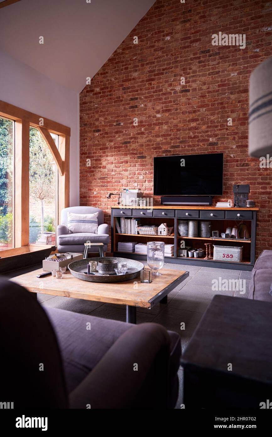 Interior Of Lounge With TV And Exposed Brick Walls In Modern Open Plan House Or Apartment Stock Photo