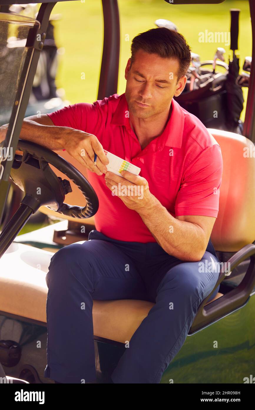 Man Sitting In Buggy Playing Round On Golf And Checking Score Card Stock Photo