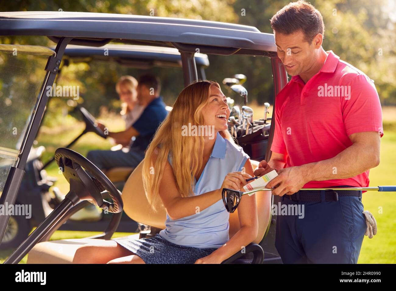 Mature And Mid Adult Couples In Buggies Playing Round On Golf Together Stock Photo