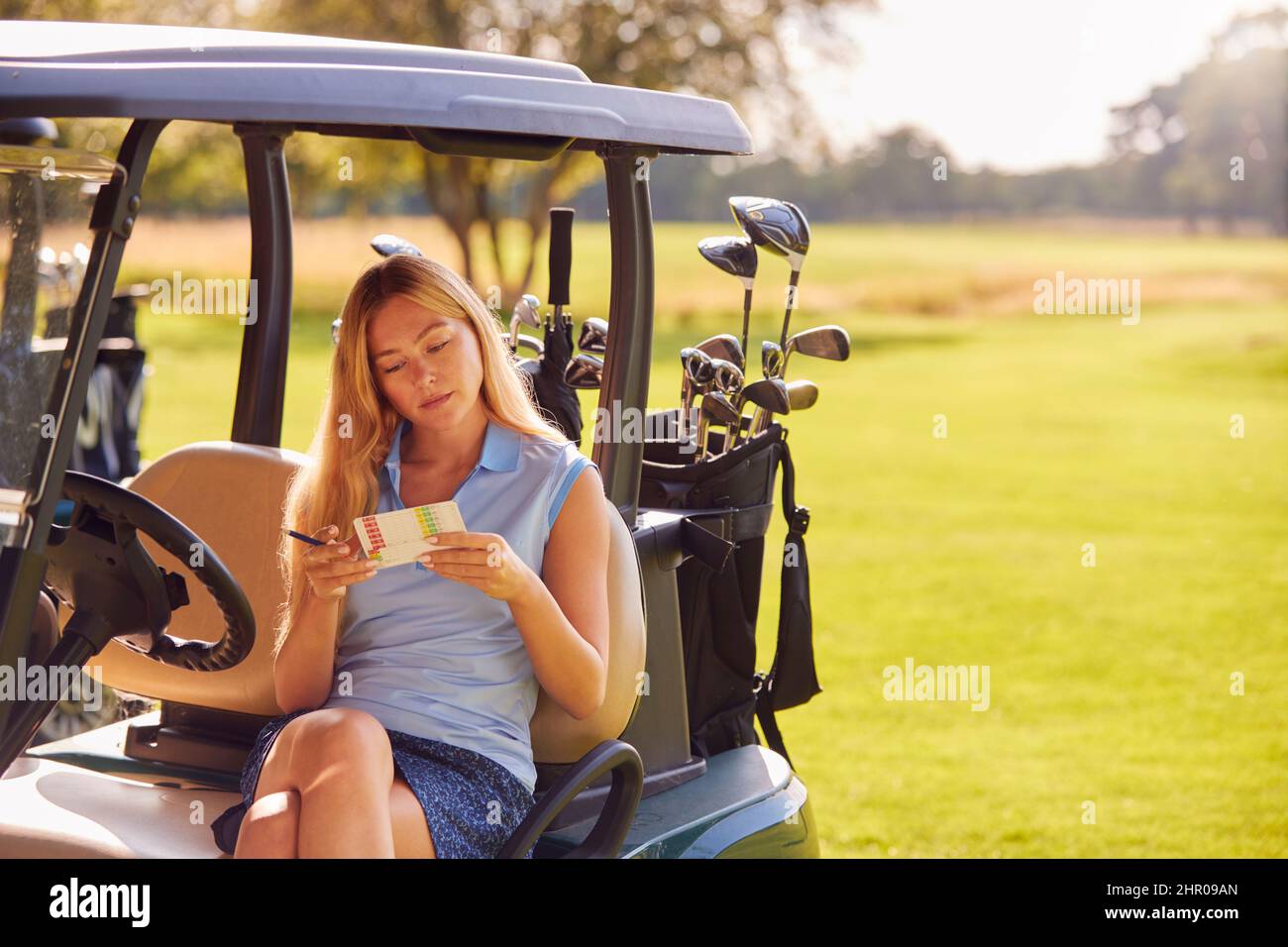 Woman Sitting In Buggy Playing Round On Golf And Checking Score Card Stock Photo
