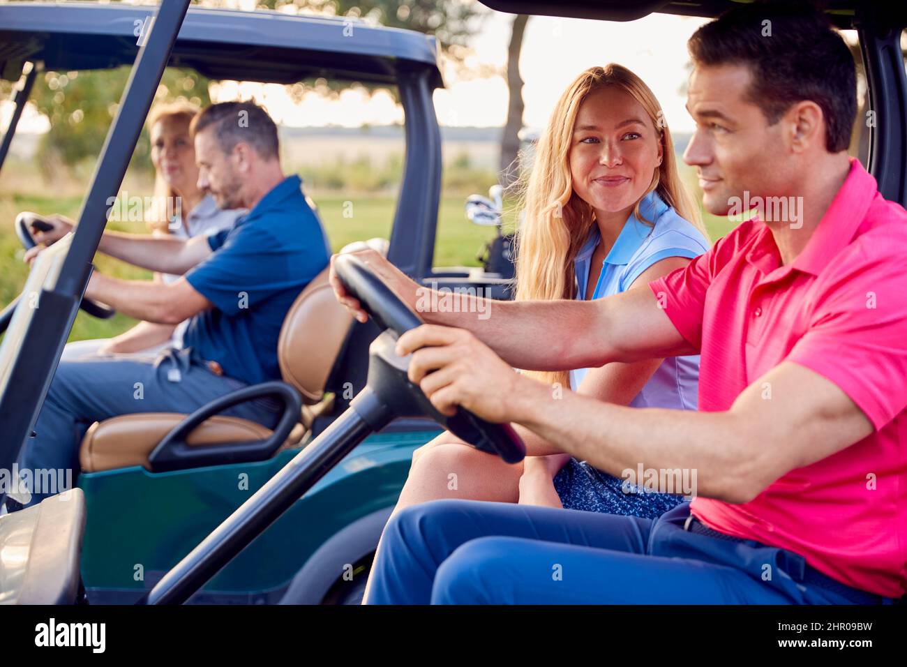 Mature And Mid Adult Couples Driving Buggies Playing Round On Golf Together Stock Photo