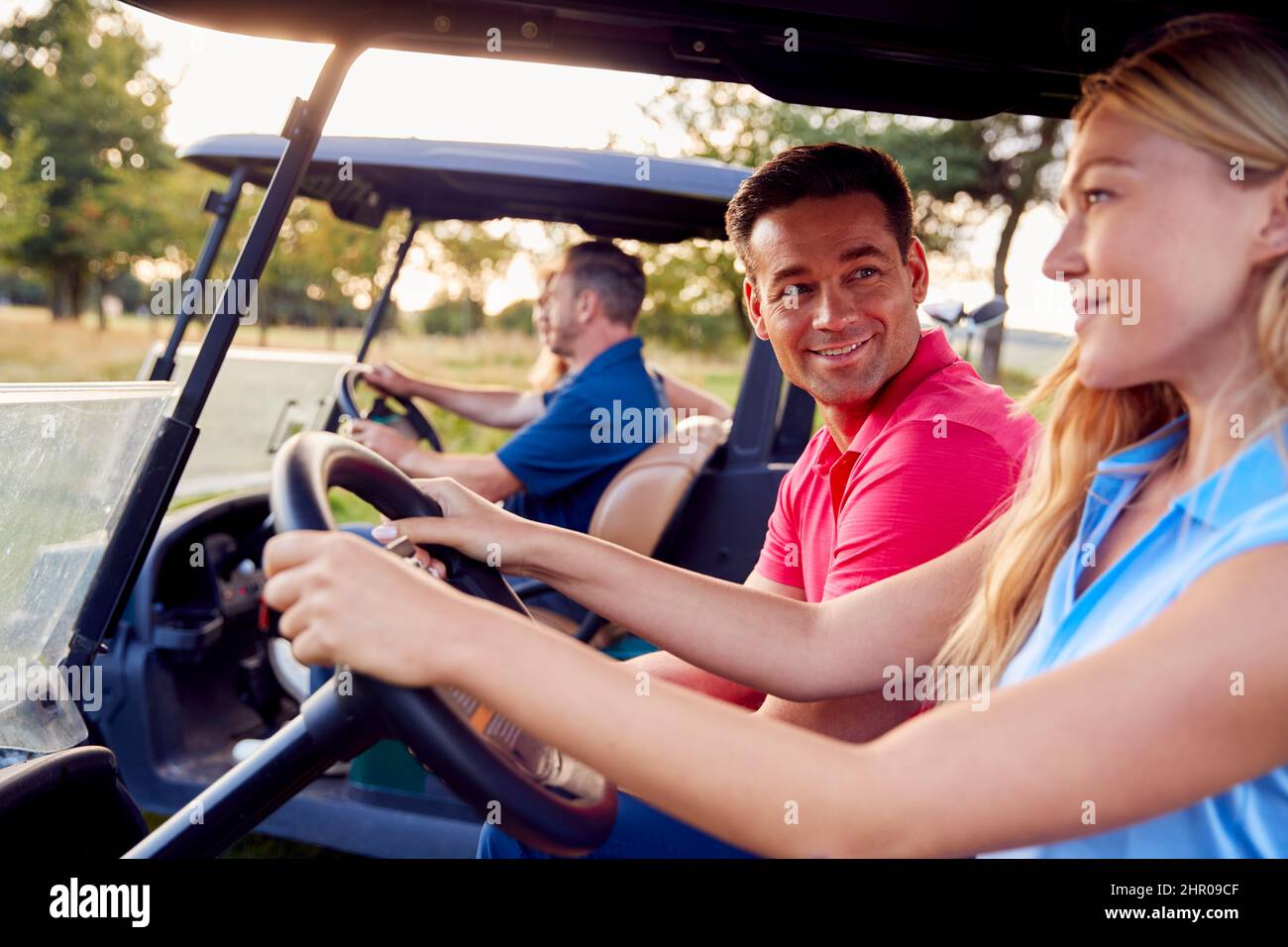 Mature And Mid Adult Couples Driving Buggies Playing Round On Golf Together Stock Photo