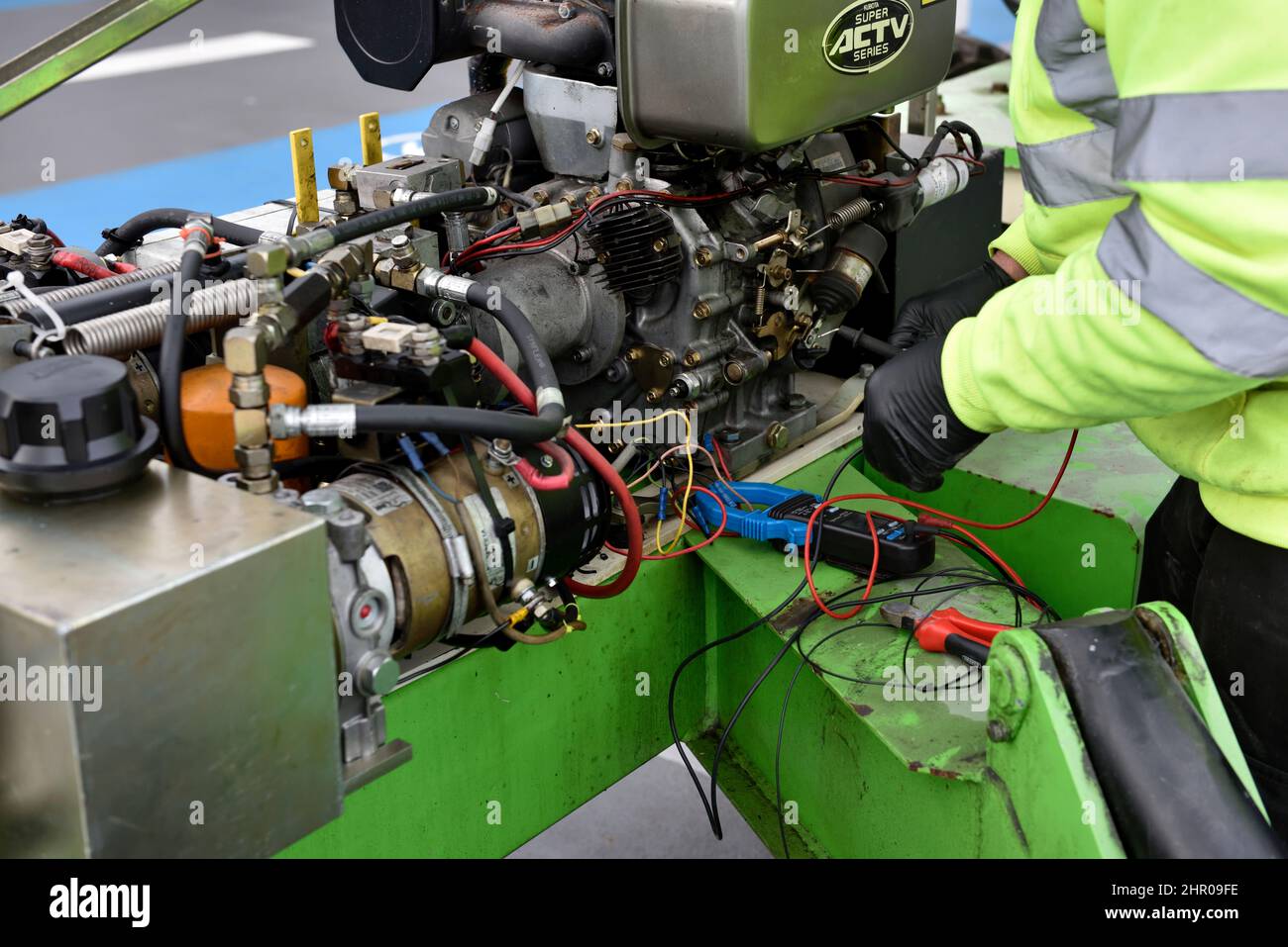 Mechanic working on electrics of engine and hydraulics of a cherry picker lift machine Stock Photo