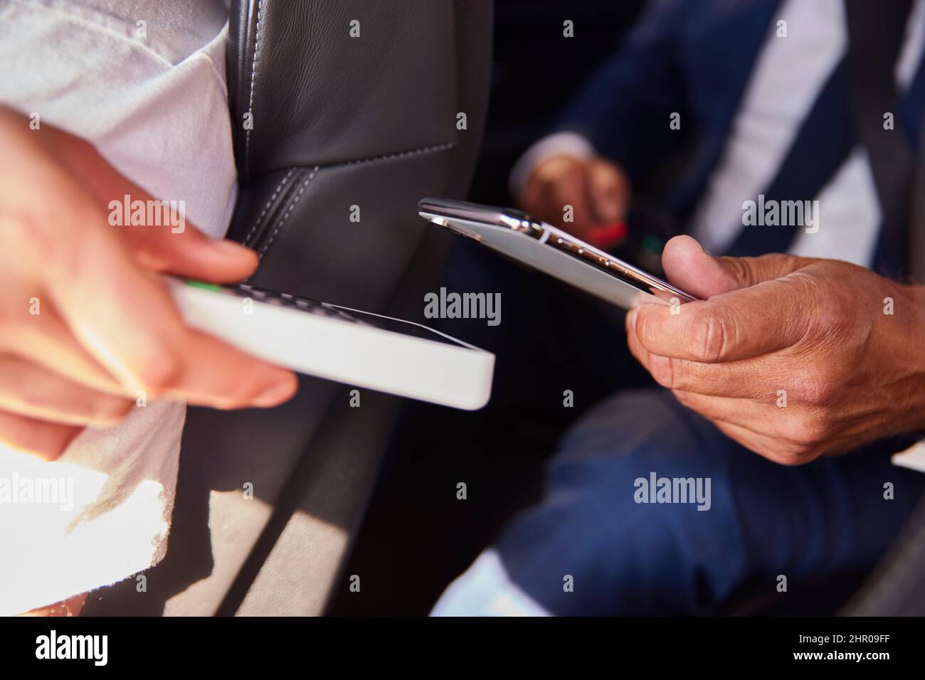 Close Up Of Businessman In Back Of Taxi Paying Fare Using Contactless Payment App On Mobile Phone Stock Photo