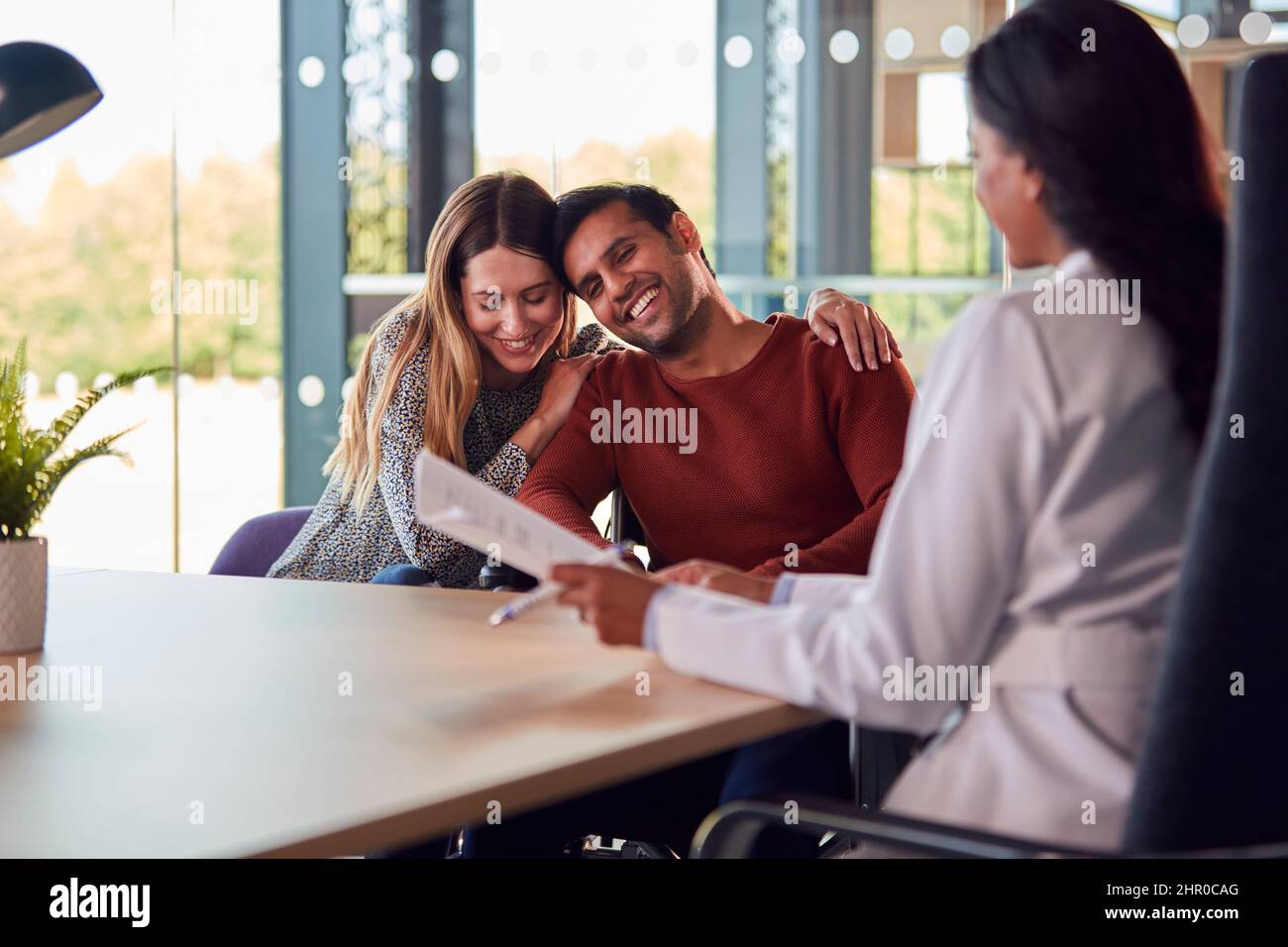 Woman Doctor Discussing Test Results With Smiling Couple n Hospital Stock Photo