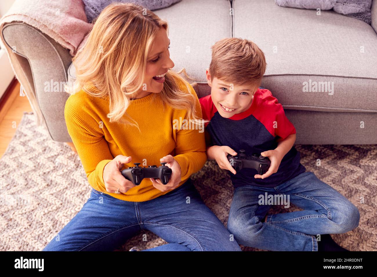 Mother And Son Sitting On Lounge Floor At Home Playing Video Game Together Stock Photo